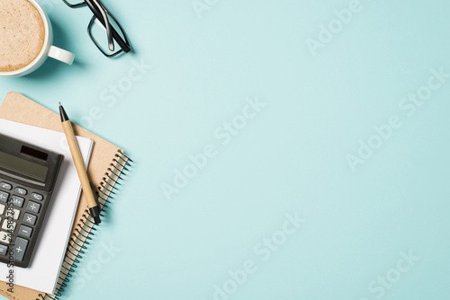 Top view photo of workplace glasses cup of frothy coffee pen organizers and calculator on isolated pastel blue background with copyspace photo