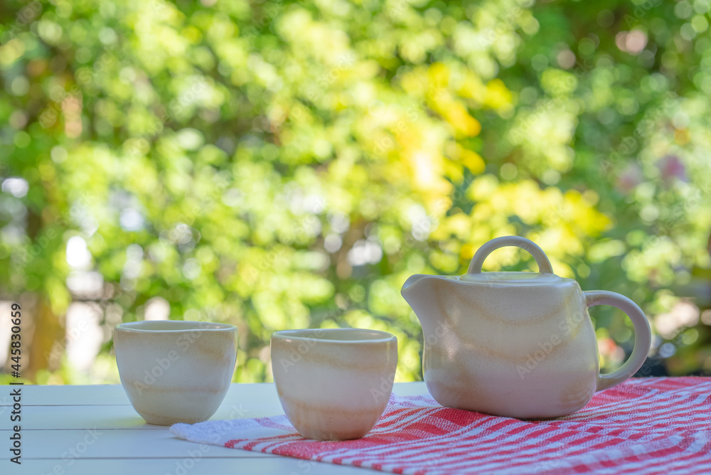 teapot and cups of green and chinese tea on white table in garden