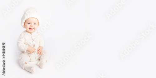 baby crawls in a warm suit and hat on a white isolated background, space for text