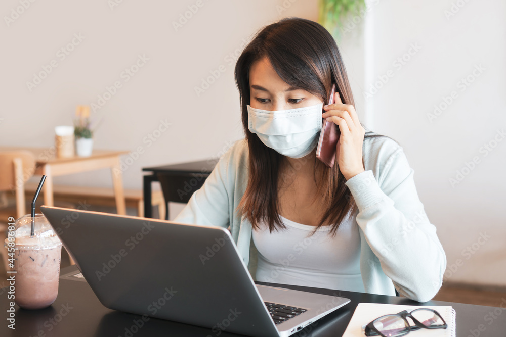 Asian woman wearing medical mask working while talk on the phone in cafe. Business and technology, health care, new normal lifestyle concept. Asian woman wearing medical mask working while talk on the phone in cafe. Business and technology, health care, new normal lifestyle concept.