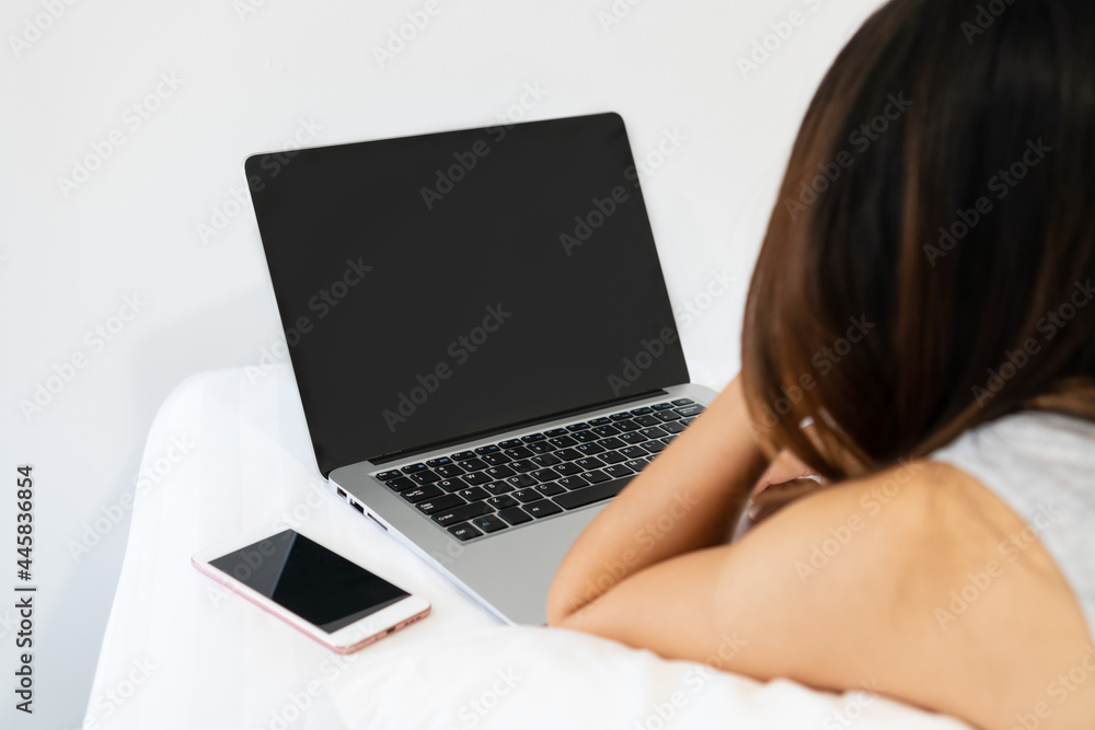 Closeup of young Asian woman using computer on bed in the morning. Technology and lifestyle, work from home concept. Copy space Closeup of young Asian woman using computer on bed in the morning. Technology and lifestyle, work from home concept. Copy space