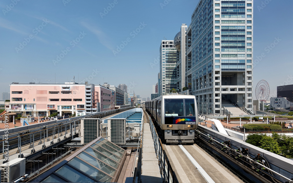 Scenery of a train traveling on the elevated rail of Yurikamome Line, passing by the famous landmark Fuji TV Building in Odaiba, Minato, Tokyo, under blue clear sunny sky (colorful painting version)