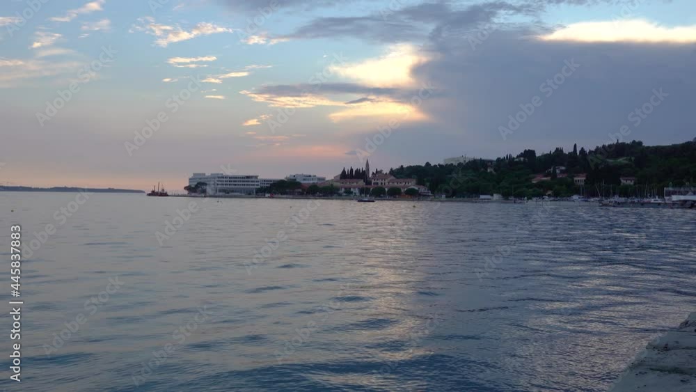 Colorful sunset over Adriatic Sea in Slovenia. Seafront walkway with buildings and hotels in the distance. Summer vibrant seascape. Beautiful golden hour with dramatic sky. Right pan, wide angle Colorful sunset over Adriatic Sea in Slovenia. Seafront walkway with buildings and hotels in the distance. Summer vibrant seascape. Beautiful golden hour with dramatic sky. Right pan, wide angle