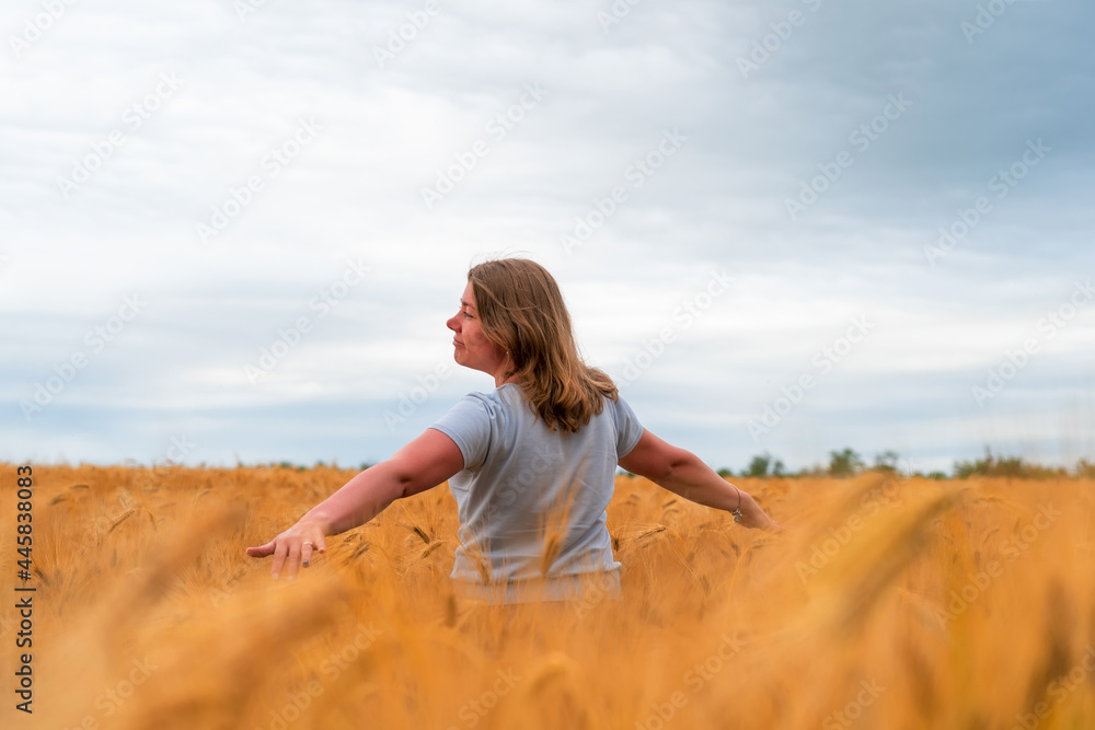 Happy girl having fun with outstretched arms in wheat field. Healthy young woman outdoors. Walking through field of rye Happy girl having fun with outstretched arms in wheat field. Healthy young woman outdoors. Walking through field of rye