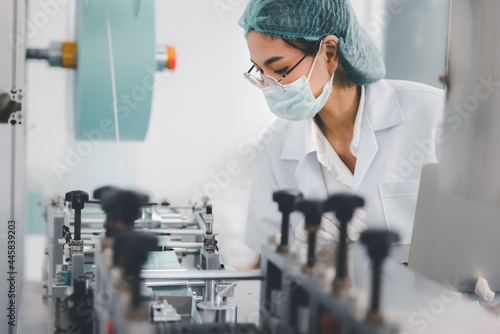 Asian female doctor or engineer working at clean medical mask production factory