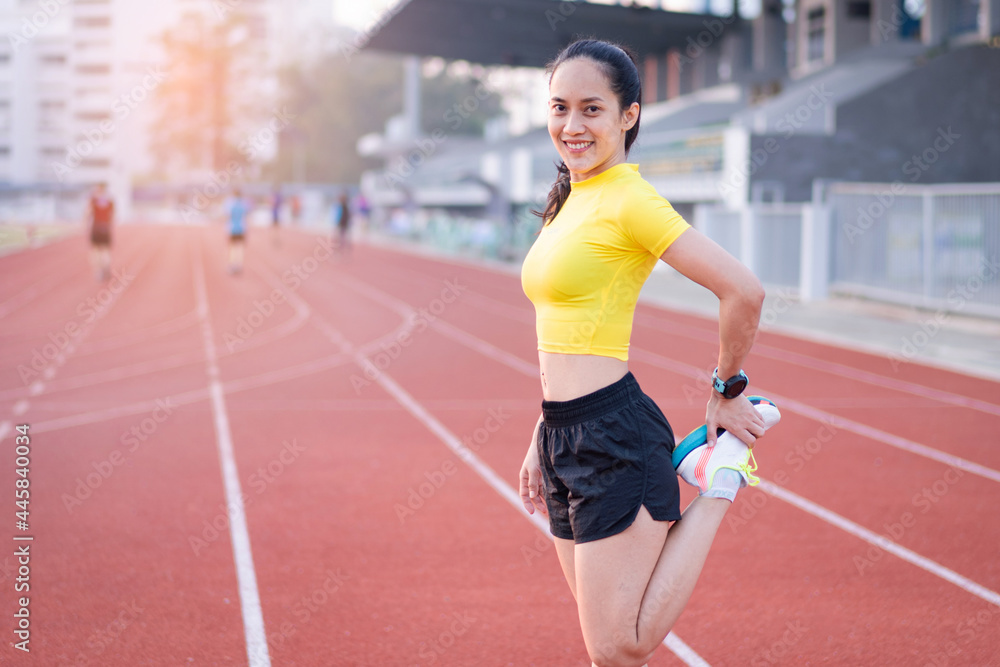 A young beautiful Asian woman in sports outfits doing stretching before workout outdoor in the city stadium  in the morning to get a healthy lifestyle. Healthy young woman doing excercise