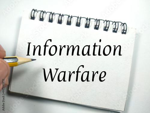Business concept.Text Information Warfare on notebook with hand holding pencil on a white background. photo