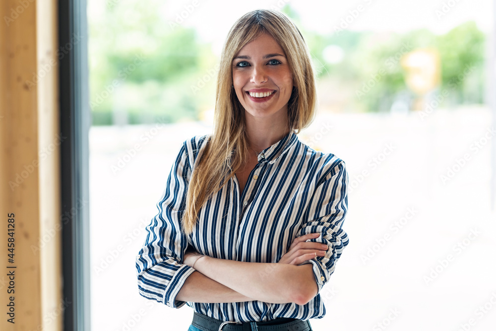 © nenetus - Pretty young businesswoman looking at camera while standing in a coworking place. © nenetus - Pretty young businesswoman looking at camera while standing in a coworking place.