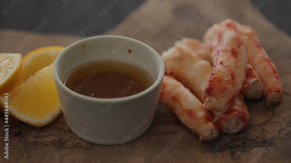 Slow motion gimbal shot of crab leg meat on a olive board with sweet lemon and dip sauce Slow motion gimbal shot of crab leg meat on a olive board with sweet lemon and dip sauce