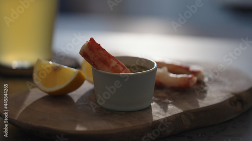 Crab leg meat on a olive board with sweet lemon and dip sauce on concrete countertop