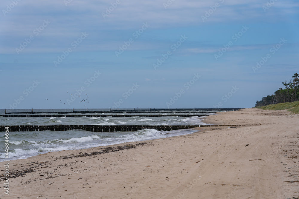 Sea waves crashing against an old wooden breakwater right on the beach