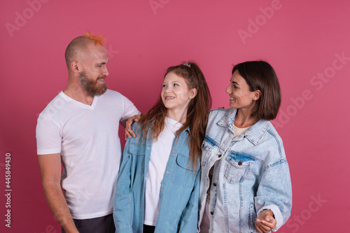 Modern mom, dad and daughter in casual on terracotta background happy family together smiling, love concept