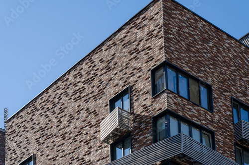 Close-up view of mounting for outdoor air conditioner on facade of new high-rise building made of decorative bricks with windows and elegant metal elements