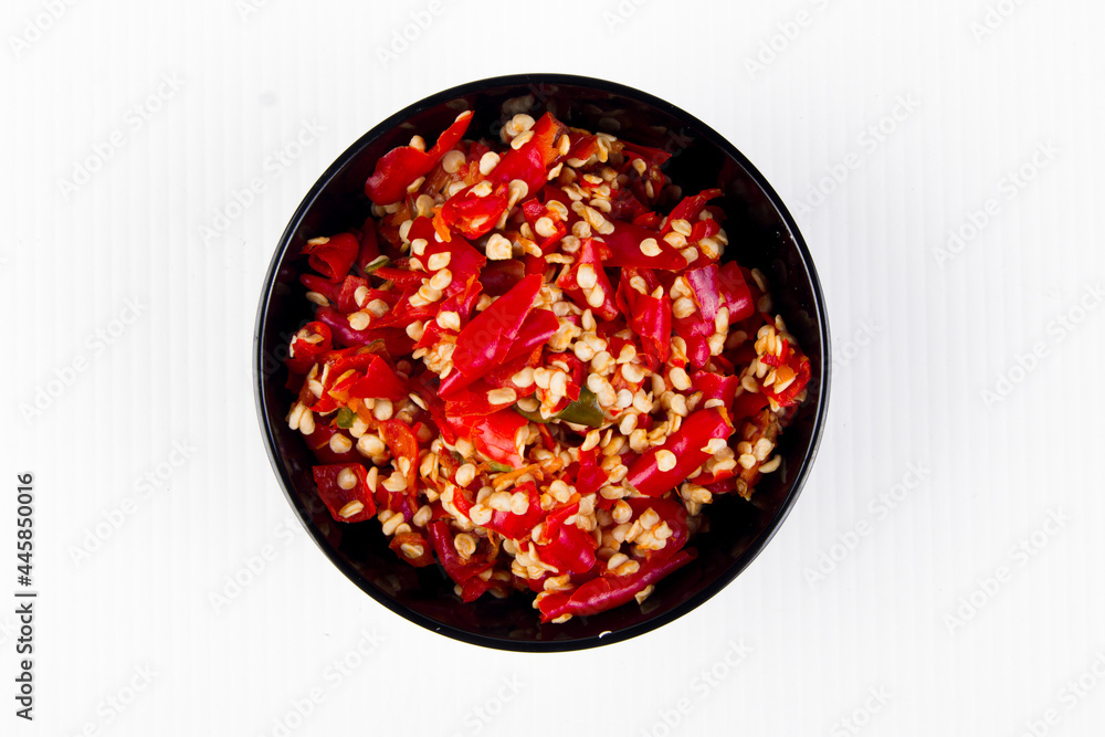 finely chopped red pepper placed in a small cup on a white background, top corner