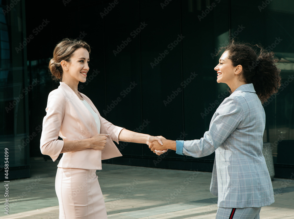 Business, people and lifestyle concept: Two business women having a casual meeting or discussion near a modern office