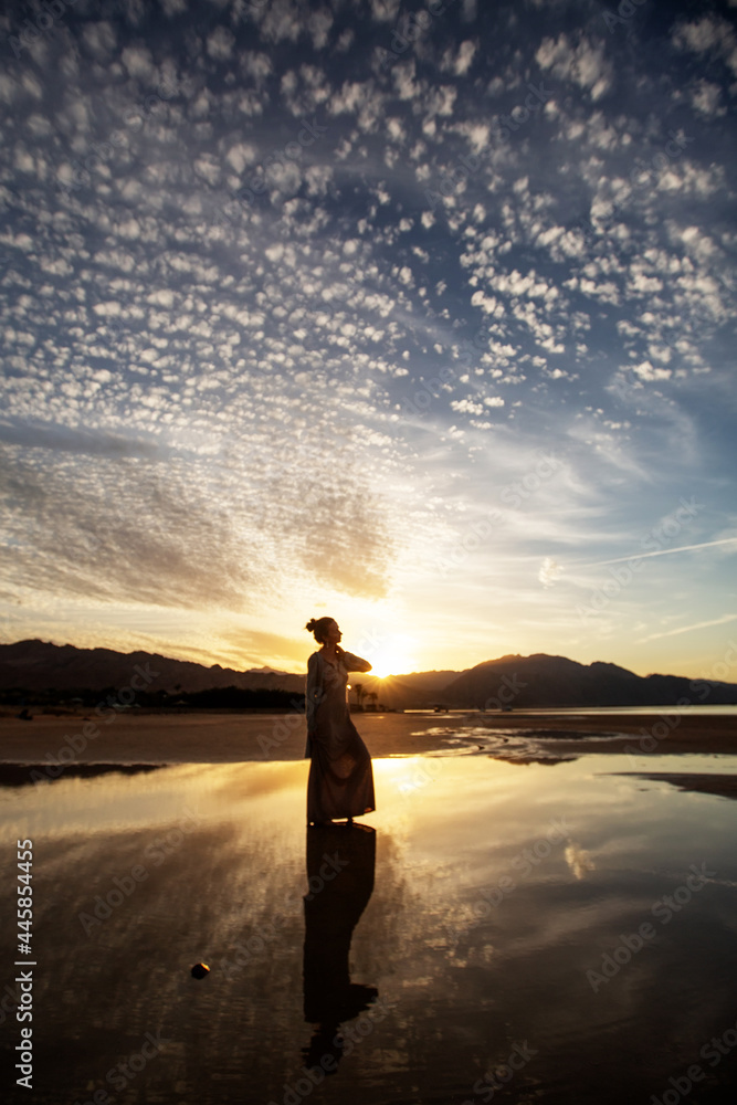 Fototapeta premium Beautiful woman dancing by the sea at sunset