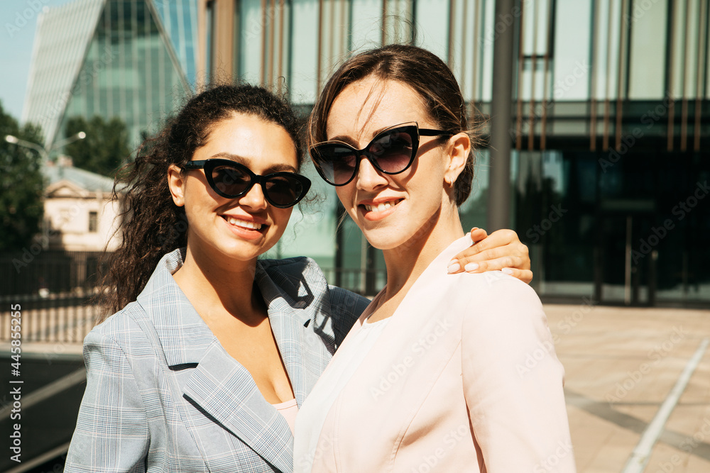Closeup portrait, two office workers wearing sunglasses standing together outdors near modern business building. Closeup portrait, two office workers wearing sunglasses standing together outdors near modern business building.