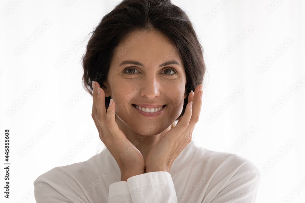 Headshot portrait of happy millennial latin female in white gown smiling caressing cheeks with shiny radiant skin. Pretty young woman looking at camera touching face enjoy antiage procedures result Headshot portrait of happy millennial latin female in white gown smiling caressing cheeks with shiny radiant skin. Pretty young woman looking at camera touching face enjoy antiage procedures result