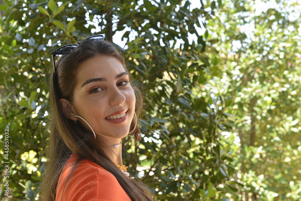 Young girl smiling in the garden. Young women portrait. Garden background with trees. Summer season Young girl smiling in the garden. Young women portrait. Garden background with trees. Summer season