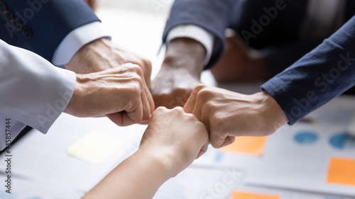 Diverse business team making group fist bump. Employees engaged in teamwork, keeping community spirit, expressing solidarity, trust, unity, friendship. Close up of multiethnic hands photo