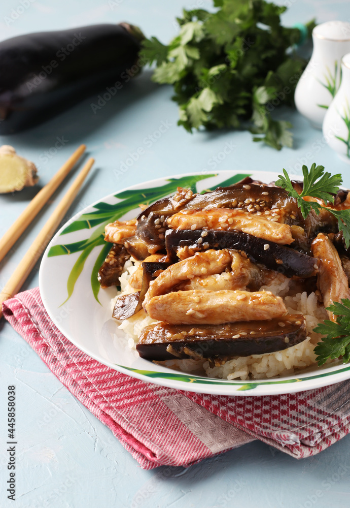 Chicken with eggplant in a spicy sauce. Delicious Asian homemade snack on light blue table.