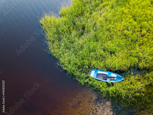 Fishing rowboat moored in the tall grass by the shore. View from above