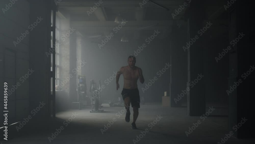 Sporty man starting to run in gym. Guy warming body before crossfit exercise Sporty man starting to run in gym. Guy warming body before crossfit exercise
