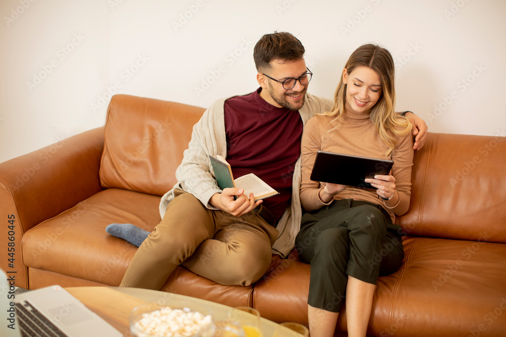 Young couple using digital tablet together while sitting on sofa at home