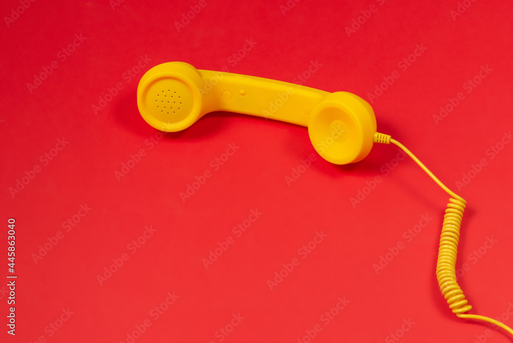 Yellow handset on red background. Copy space. Yellow handset on red background. Copy space.