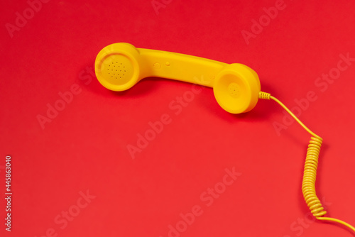 Fotografie Yellow handset on red background. Copy space.