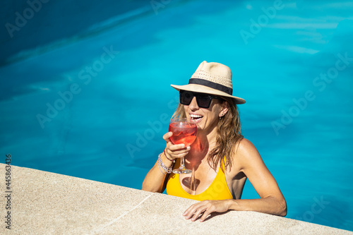 Canvas Print Woman drinking cocktail into swimming pool