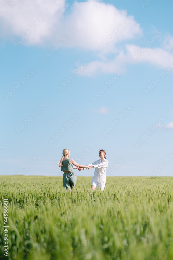 Portrait of two fair-haired girls in fashionable and stylish clothes, against the background of a field. Nature, vacation, relax and lifestyle. Fashion concept. Portrait of two fair-haired girls in fashionable and stylish clothes, against the background of a field. Nature, vacation, relax and lifestyle. Fashion concept.