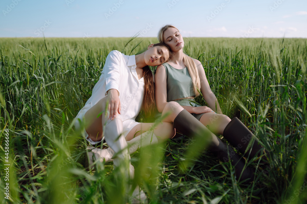 Portrait of two fair-haired girls in fashionable and stylish clothes, against the background of a field. Nature, vacation, relax and lifestyle. Fashion concept. Portrait of two fair-haired girls in fashionable and stylish clothes, against the background of a field. Nature, vacation, relax and lifestyle. Fashion concept.
