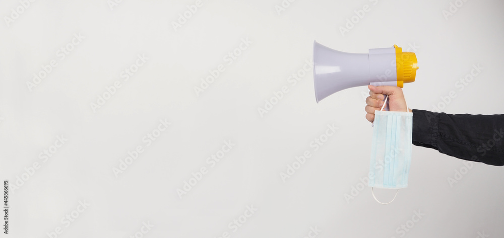 Megaphone and face mask in Male Hand and he wear black shirt on white background. Studio shooting. Megaphone and face mask in Male Hand and he wear black shirt on white background. Studio shooting.
