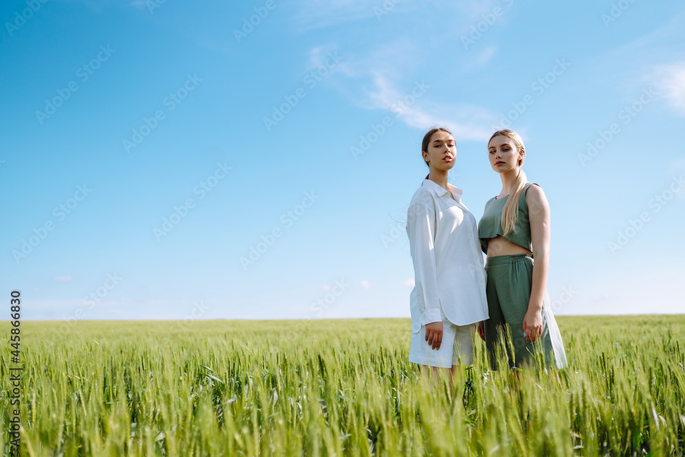 Portrait of two fair-haired girls in fashionable and stylish clothes, against the background of a field. Nature, vacation, relax and lifestyle. Fashion concept. Portrait of two fair-haired girls in fashionable and stylish clothes, against the background of a field. Nature, vacation, relax and lifestyle. Fashion concept.
