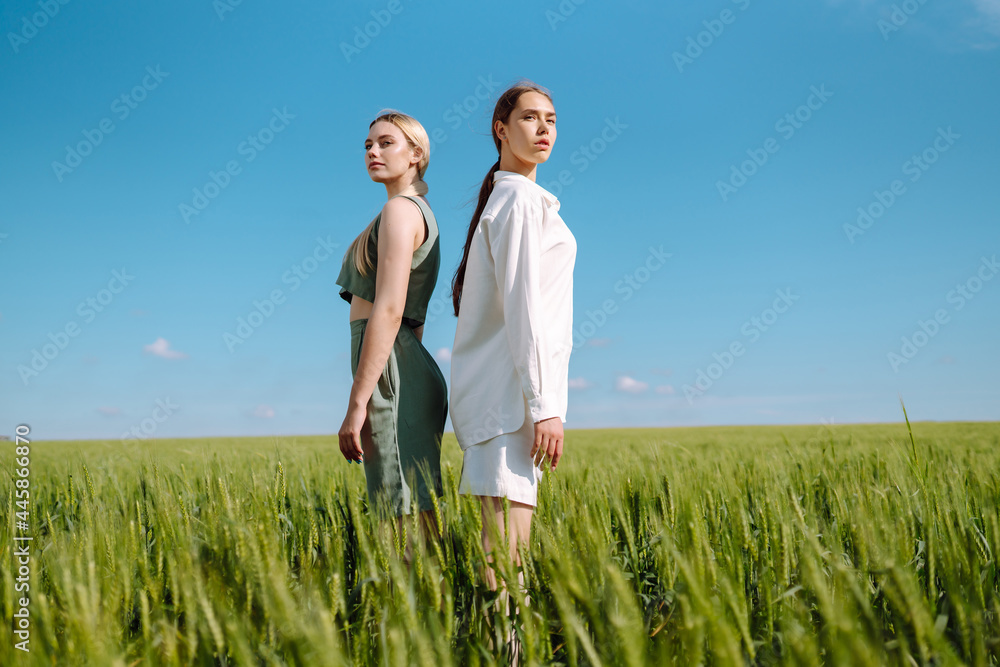Portrait of two fair-haired girls in fashionable and stylish clothes, against the background of a field. Nature, vacation, relax and lifestyle. Fashion concept. Portrait of two fair-haired girls in fashionable and stylish clothes, against the background of a field. Nature, vacation, relax and lifestyle. Fashion concept.