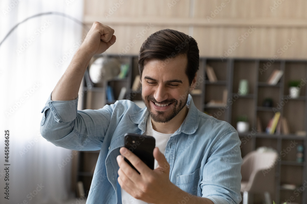 Overjoyed sincere handsome happy young man looking at smartphone screen, celebrating getting amazing unbelievable news, online lottery giveaway win, victory notification, internet success concept. Overjoyed sincere handsome happy young man looking at smartphone screen, celebrating getting amazing unbelievable news, online lottery giveaway win, victory notification, internet success concept.