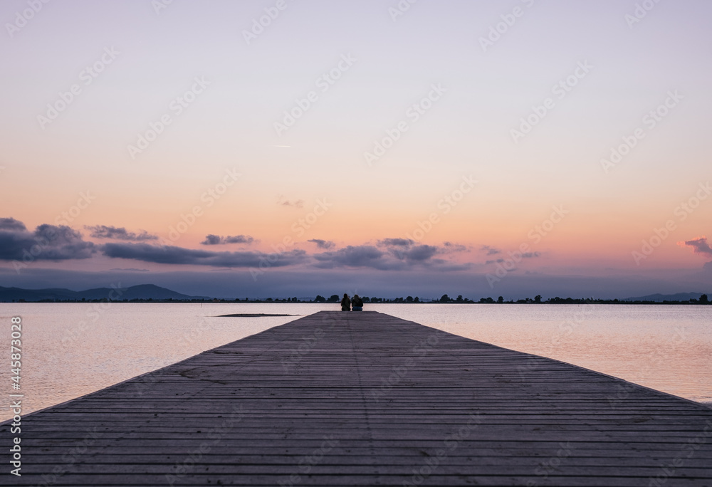 Anonymous persons sitting on end of pier