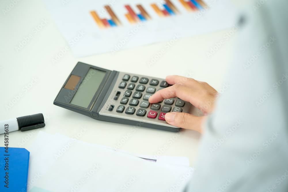 Focusing on calculator and hand on its for meeting business seminar sales chart on paper Focusing on calculator and hand on its for meeting business seminar sales chart on paper