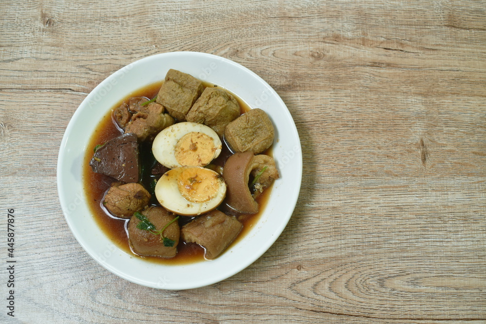 boiled half cut egg with tofu in herb brown soup and pork leg on plate