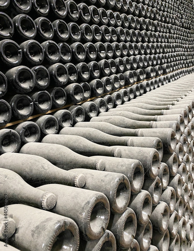 old bottles of sparkling wine, covered with dust and cobwebs, lie in stacks in the wine cellar. Bottles of champagne in the process of maturation © proxima13