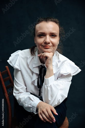 Portrait of a caucasian woman sitting on a chair in the studio on a black background