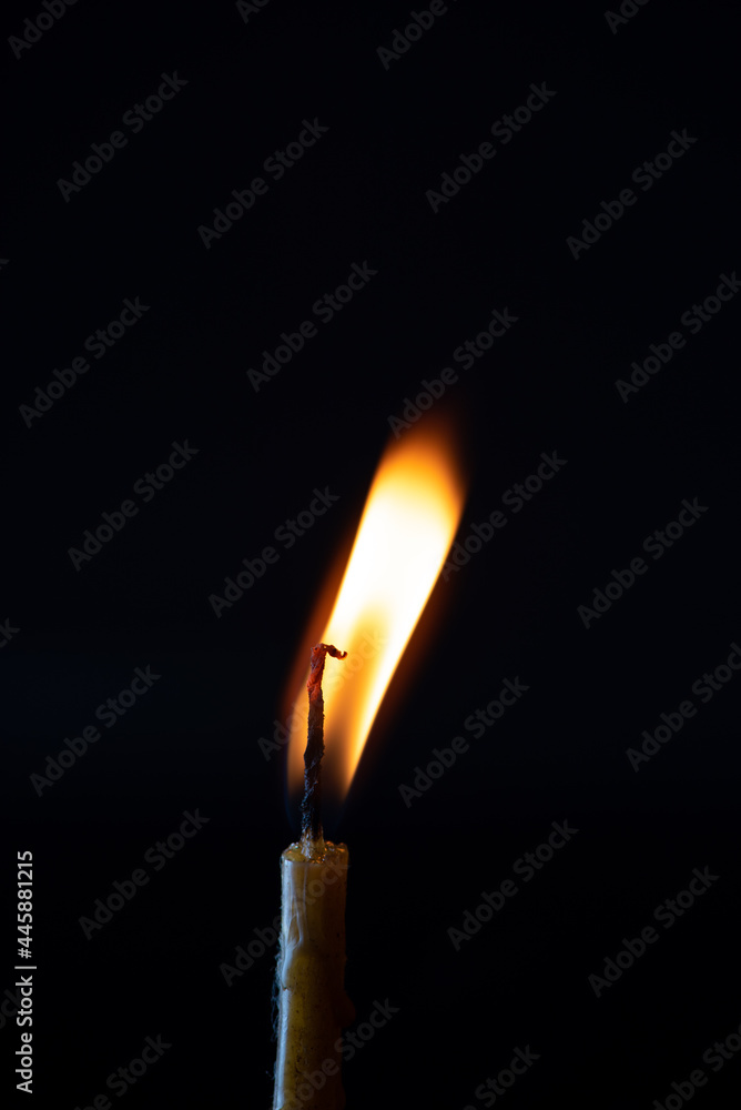 The bright flame of a dying candle on a dark background close-up. The bright flame of a dying candle on a dark background close-up.