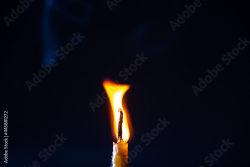 The bright flame of a dying candle on a dark background close-up. © shymar27