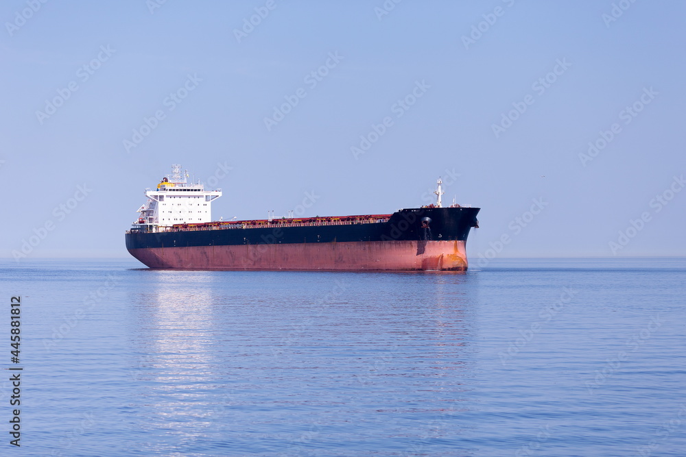 Large cargo ship anchored in the St. Lawrence River seen during a sunny summer afternoon near Tadoussac, Quebec, Canada