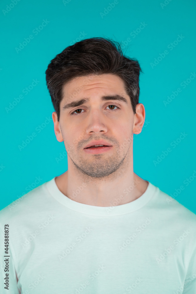 Fototapeta premium Frustrated european man over teal wall background. Guy is tired, bored of work or studying, he disappointed, helpless