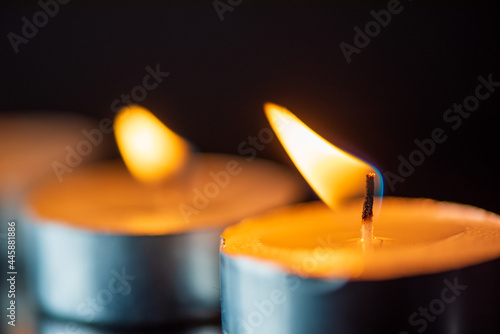 The bright flame of a dying candle on a dark background close-up.
