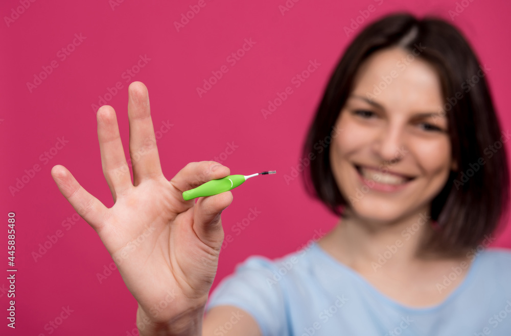 Beautiful happy young woman using interdental brush on the pink background Beautiful happy young woman using interdental brush on the pink background