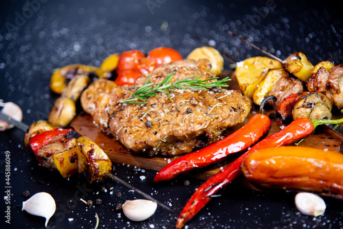 Steak on a wooden cutting board and black background sprinkled with salt and pepper.