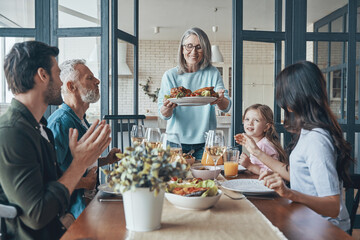 Happy multi-generation family communicating and smiling while having dinner together